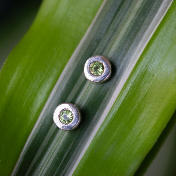 Beautiful bezel set stud earrings featuring bright 4mm peridot gems set in a modern and minimal sterling silver stud