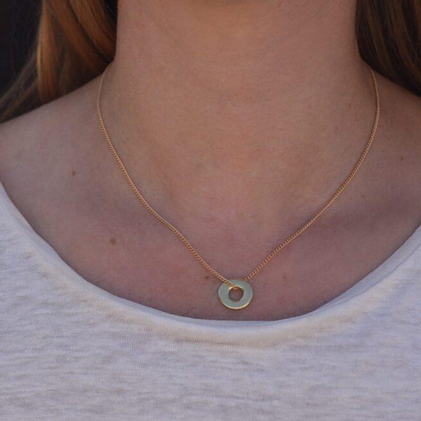 an image of the solid 18k gold mini ina necklace, a delicate circular necklace on a 16 inch chain, on a model for scale.